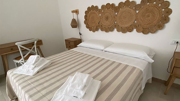 Camera matrimoniale con arredi in legno e biancheria a righe